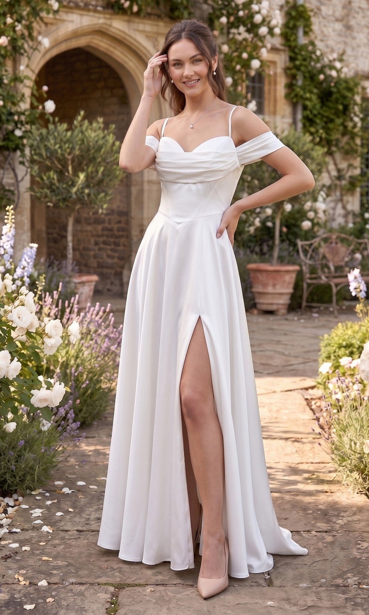 Wearing the Long Prom Dress: Chicas C2575 in Off White, a woman stands outdoors on a stone path, surrounded by flowers and greenery; her satin gown features an off-the-shoulder neckline, flowing A-line skirt, and thigh-high slit.